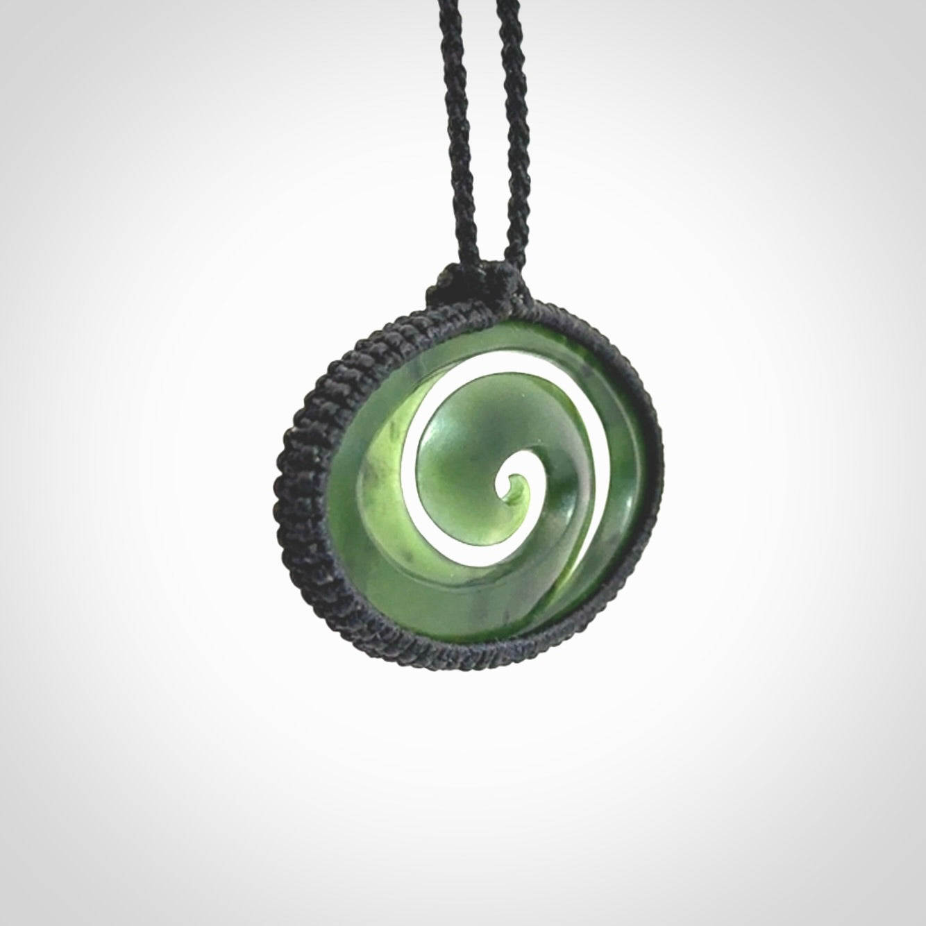This picture shows a medium sized hand carved jade koru pendant. It is a darker green colour which is quite translucent where the jade is thin. The cord is bound in a macrame style and is adjustable so that you can position the pendant where it suits you best.