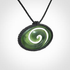 This picture shows a medium sized hand carved jade koru pendant. It is a darker green colour which is quite translucent where the jade is thin. The cord is bound in a macrame style and is adjustable so that you can position the pendant where it suits you best.