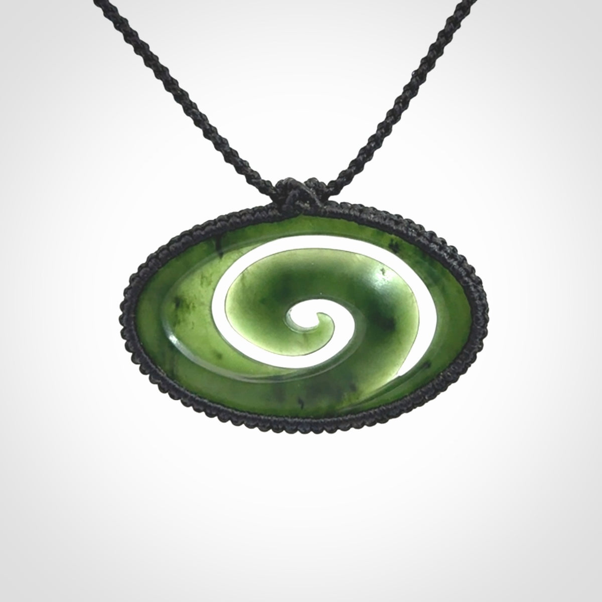 This picture shows a medium sized hand carved jade koru pendant. It is a darker green colour which is quite translucent where the jade is thin. The cord is bound in a macrame style and is adjustable so that you can position the pendant where it suits you best.