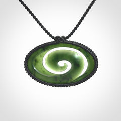 This picture shows a medium sized hand carved jade koru pendant. It is a darker green colour which is quite translucent where the jade is thin. The cord is bound in a macrame style and is adjustable so that you can position the pendant where it suits you best.