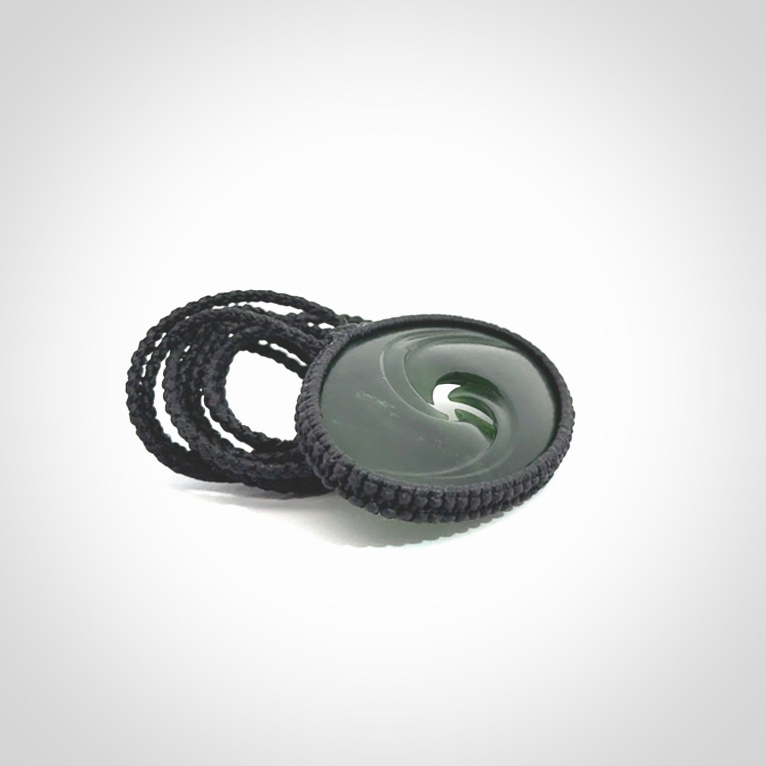 This picture shows a medium sized hand carved jade koru pendant. It is a darker green colour which is quite translucent where the jade is thin. The cord is bound in a macrame style and is adjustable so that you can position the pendant where it suits you best.