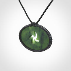 This picture shows a medium sized hand carved jade koru pendant. It is a darker green colour which is quite translucent where the jade is thin. The cord is bound in a macrame style and is adjustable so that you can position the pendant where it suits you best.