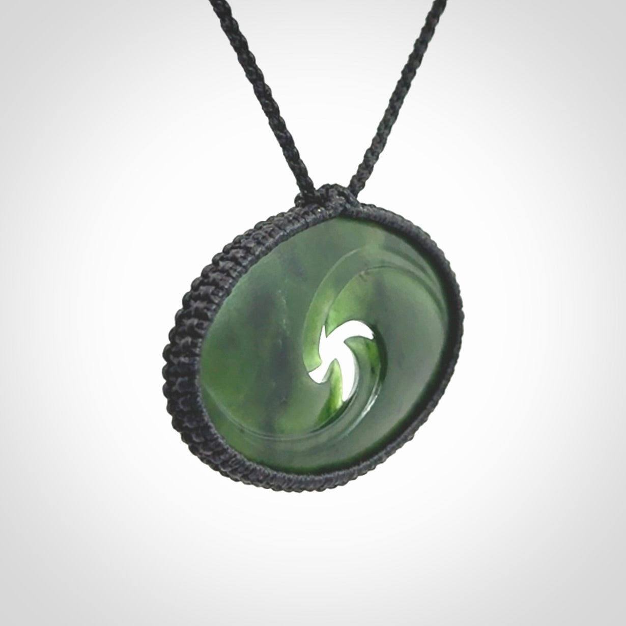 This picture shows a medium sized hand carved jade koru pendant. It is a darker green colour which is quite translucent where the jade is thin. The cord is bound in a macrame style and is adjustable so that you can position the pendant where it suits you best.