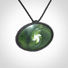 This picture shows a medium sized hand carved jade koru pendant. It is a darker green colour which is quite translucent where the jade is thin. The cord is bound in a macrame style and is adjustable so that you can position the pendant where it suits you best.