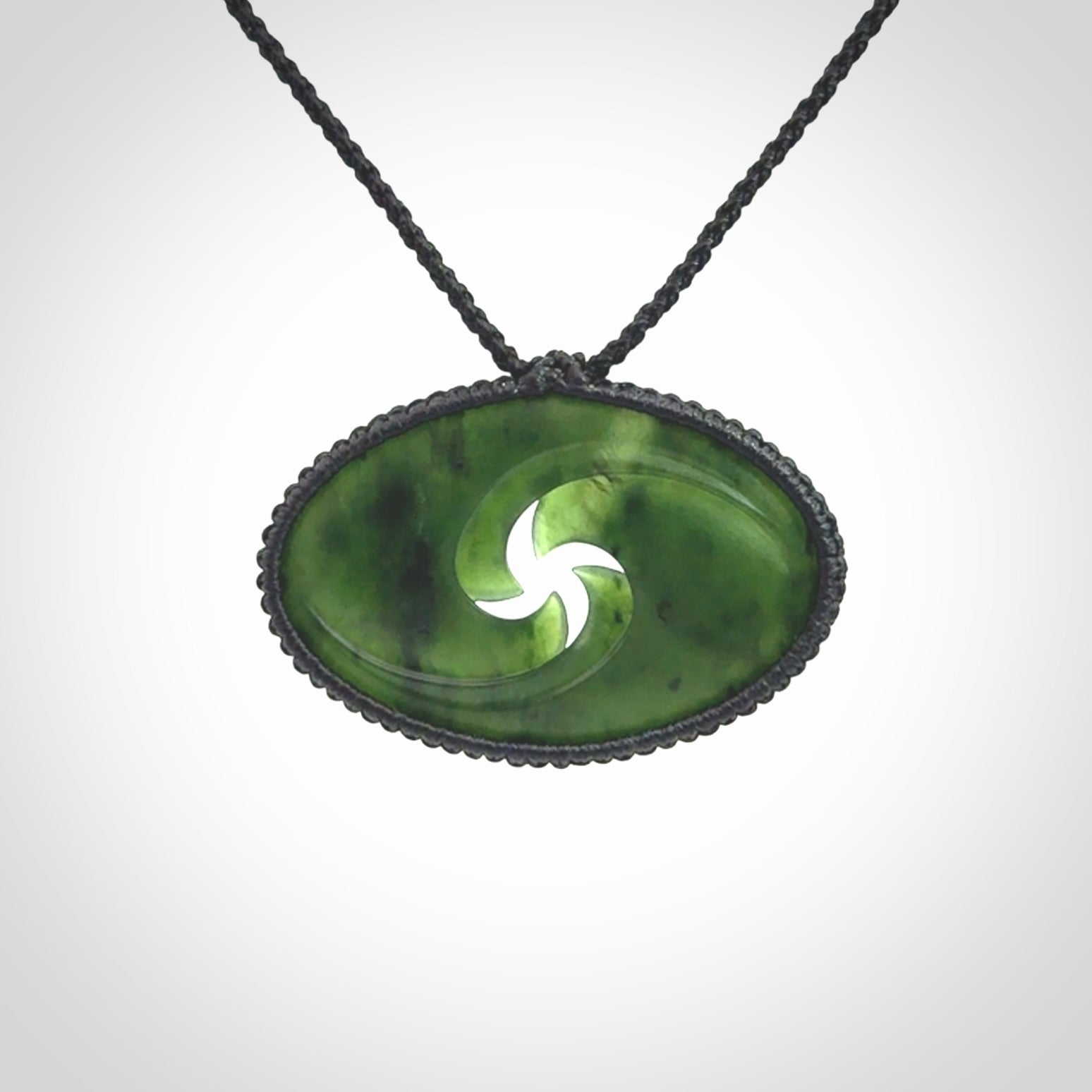 This picture shows a medium sized hand carved jade koru pendant. It is a darker green colour which is quite translucent where the jade is thin. The cord is bound in a macrame style and is adjustable so that you can position the pendant where it suits you best.