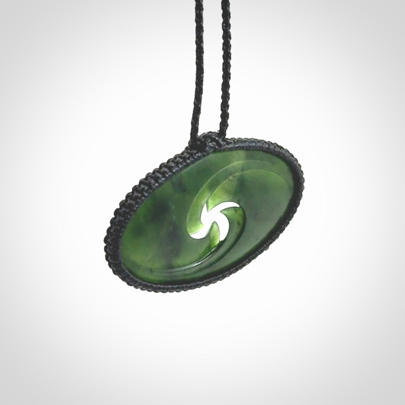 This picture shows a medium sized hand carved jade koru pendant. It is a darker green colour which is quite translucent where the jade is thin. The cord is bound in a macrame style and is adjustable so that you can position the pendant where it suits you best.