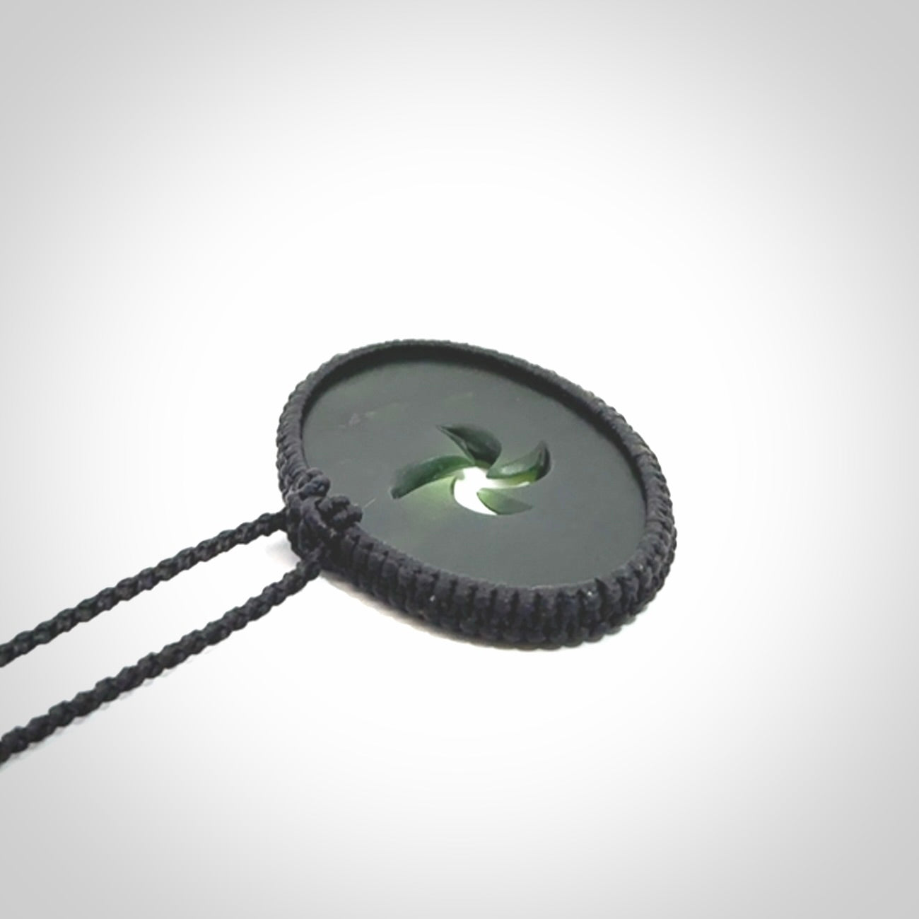 This picture shows a medium sized hand carved jade koru pendant. It is a darker green colour which is quite translucent where the jade is thin. The cord is bound in a macrame style and is adjustable so that you can position the pendant where it suits you best.