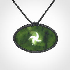 This picture shows a medium sized hand carved jade koru pendant. It is a darker green colour which is quite translucent where the jade is thin. The cord is bound in a macrame style and is adjustable so that you can position the pendant where it suits you best.