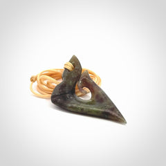 This photo shows a matau, hook, pendant carved from New Zealand Totoweka Pounamu, Jade. We provide this piece with an adjustable beige coloured cord.