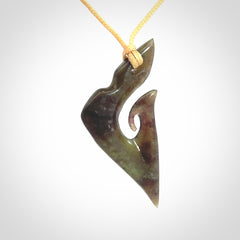 This photo shows a matau, hook, pendant carved from New Zealand Totoweka Pounamu, Jade. We provide this piece with an adjustable beige coloured cord.