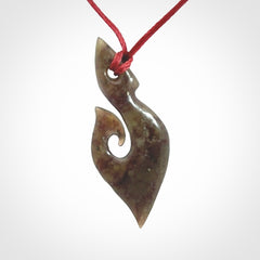 This photo shows a contemporary koru pendant carved from New Zealand Totoweka Jade. We provide this piece with an adjustable red cord.