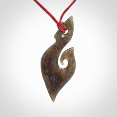 This photo shows a contemporary koru pendant carved from New Zealand Totoweka Jade. We provide this piece with an adjustable red cord.