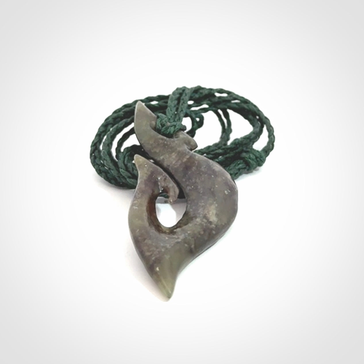 This photo shows a matau, hook, pendant carved from New Zealand Totoweka Pounamu, Jade. We provide this piece with an adjustable green coloured cord.