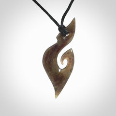 This photo shows a contemporary koru pendant carved from New Zealand Totoweka Jade. We provide this piece with a black fixed length cord.