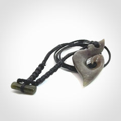 This photo shows a contemporary koru pendant carved from New Zealand Totoweka Jade. We provide this piece with a black fixed length cord.