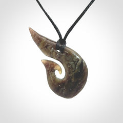 This photo shows a contemporary koru pendant carved from New Zealand Totoweka Jade. We provide this piece with a black fixed length cord.
