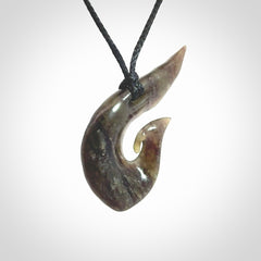 This photo shows a contemporary koru pendant carved from New Zealand Totoweka Jade. We provide this piece with a black fixed length cord.