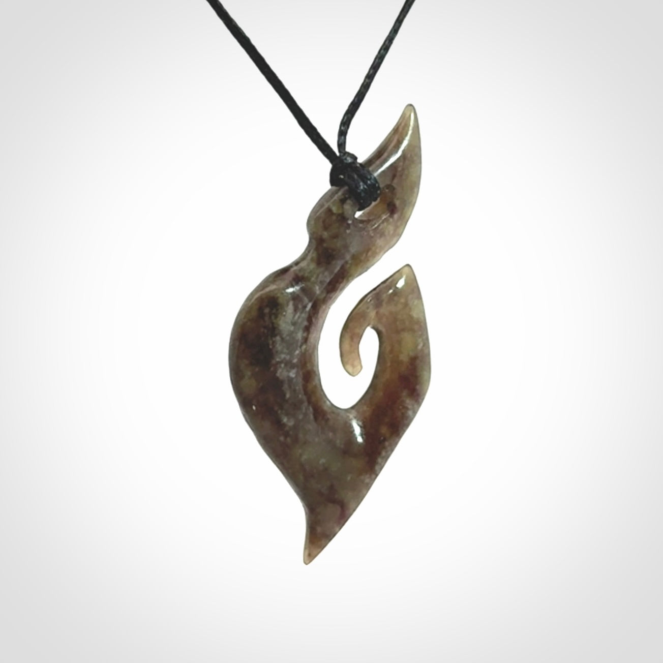This photo shows a contemporary koru pendant carved from New Zealand Totoweka Jade. We provide this piece with a black fixed length cord.