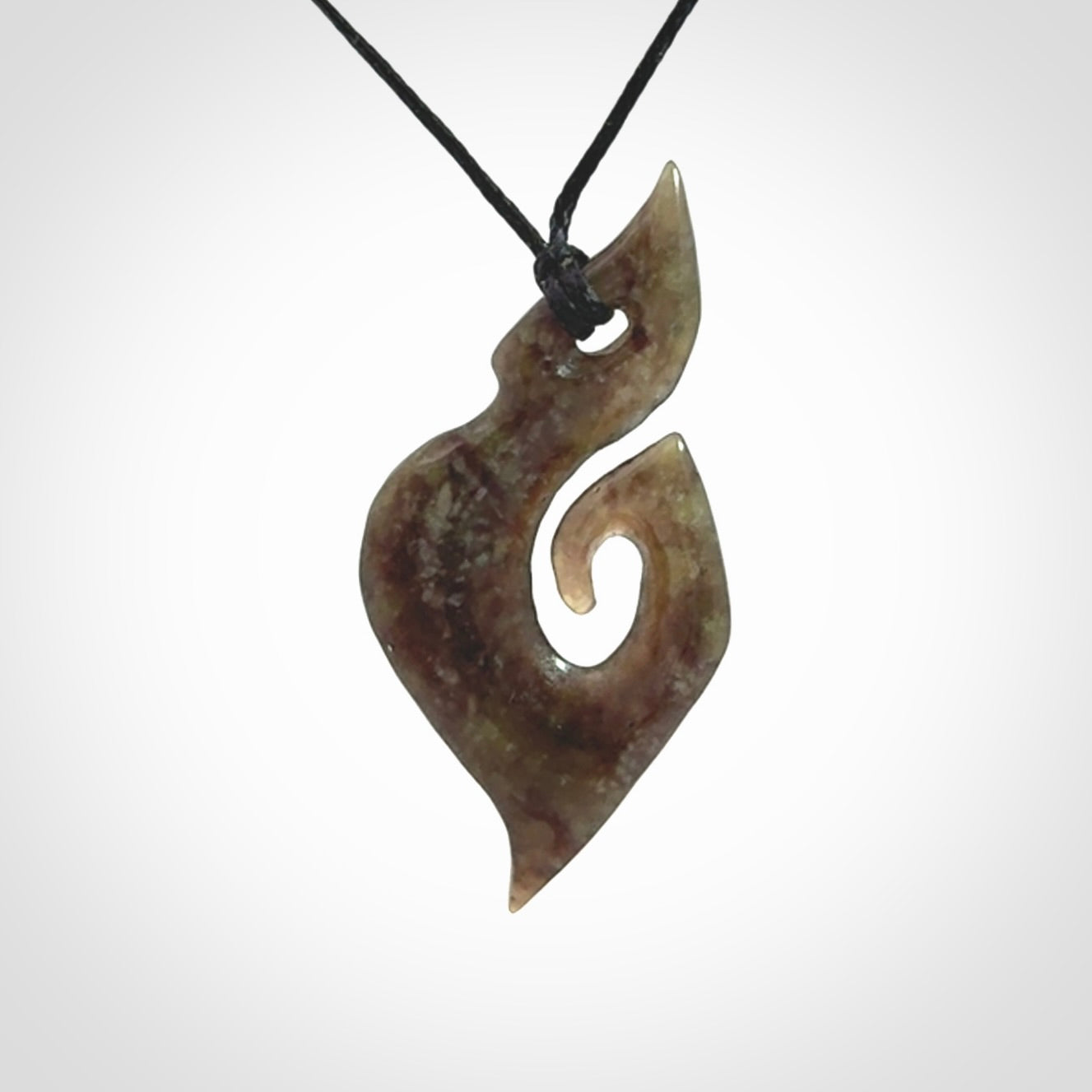 This photo shows a contemporary koru pendant carved from New Zealand Totoweka Jade. We provide this piece with a black fixed length cord.