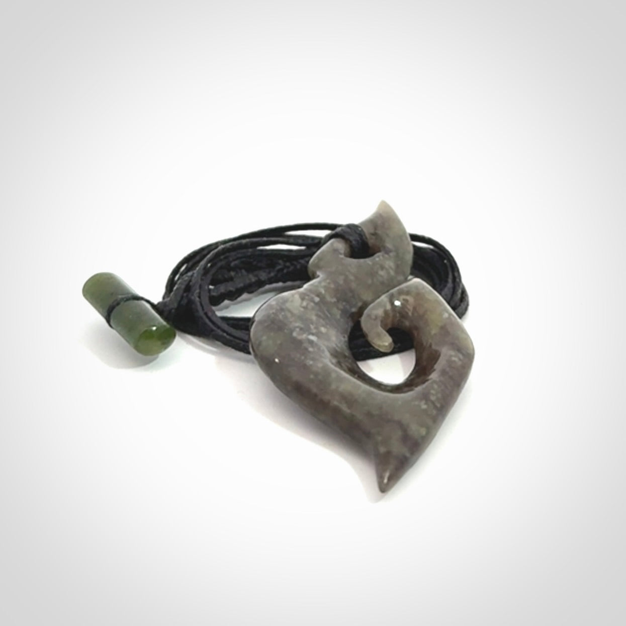 This photo shows a contemporary koru pendant carved from New Zealand Totoweka Jade. We provide this piece with a black fixed length cord.