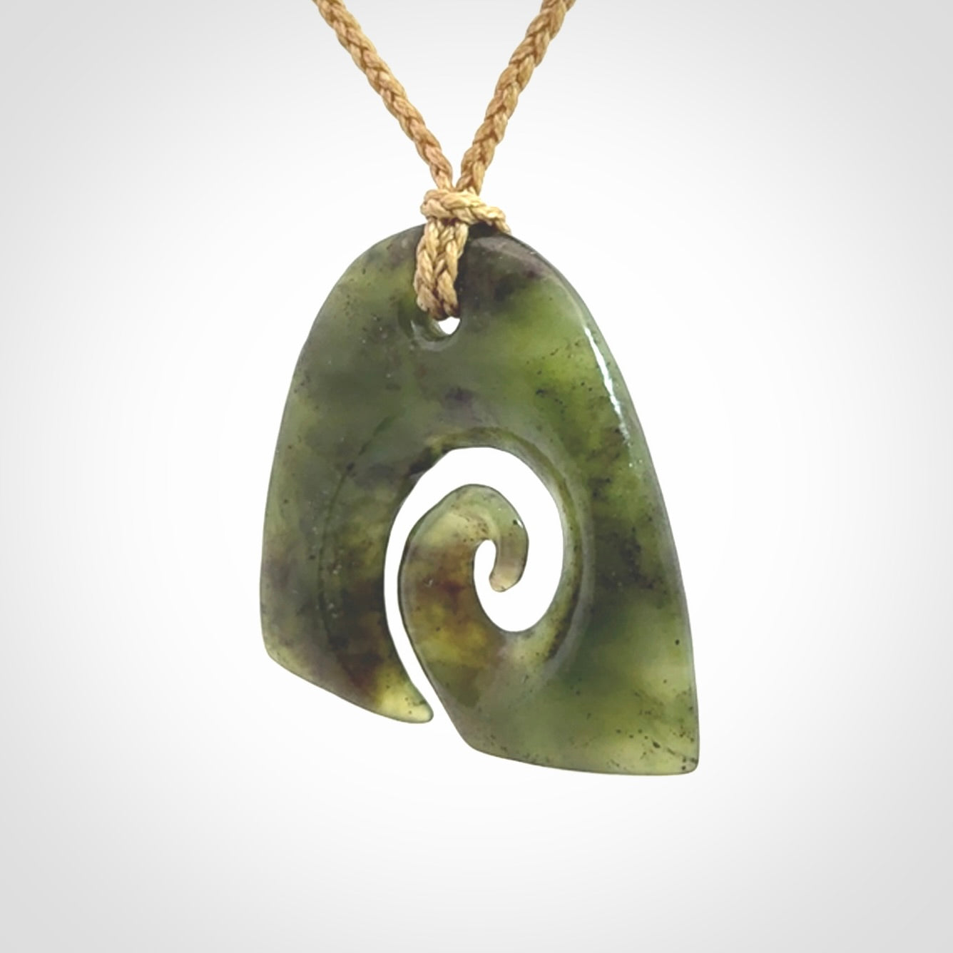 This photo shows a contemporary koru pendant carved from New Zealand Jade. We provide this piece with a tan fixed length cord.