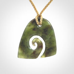 This photo shows a contemporary koru pendant carved from New Zealand Jade. We provide this piece with a tan fixed length cord.