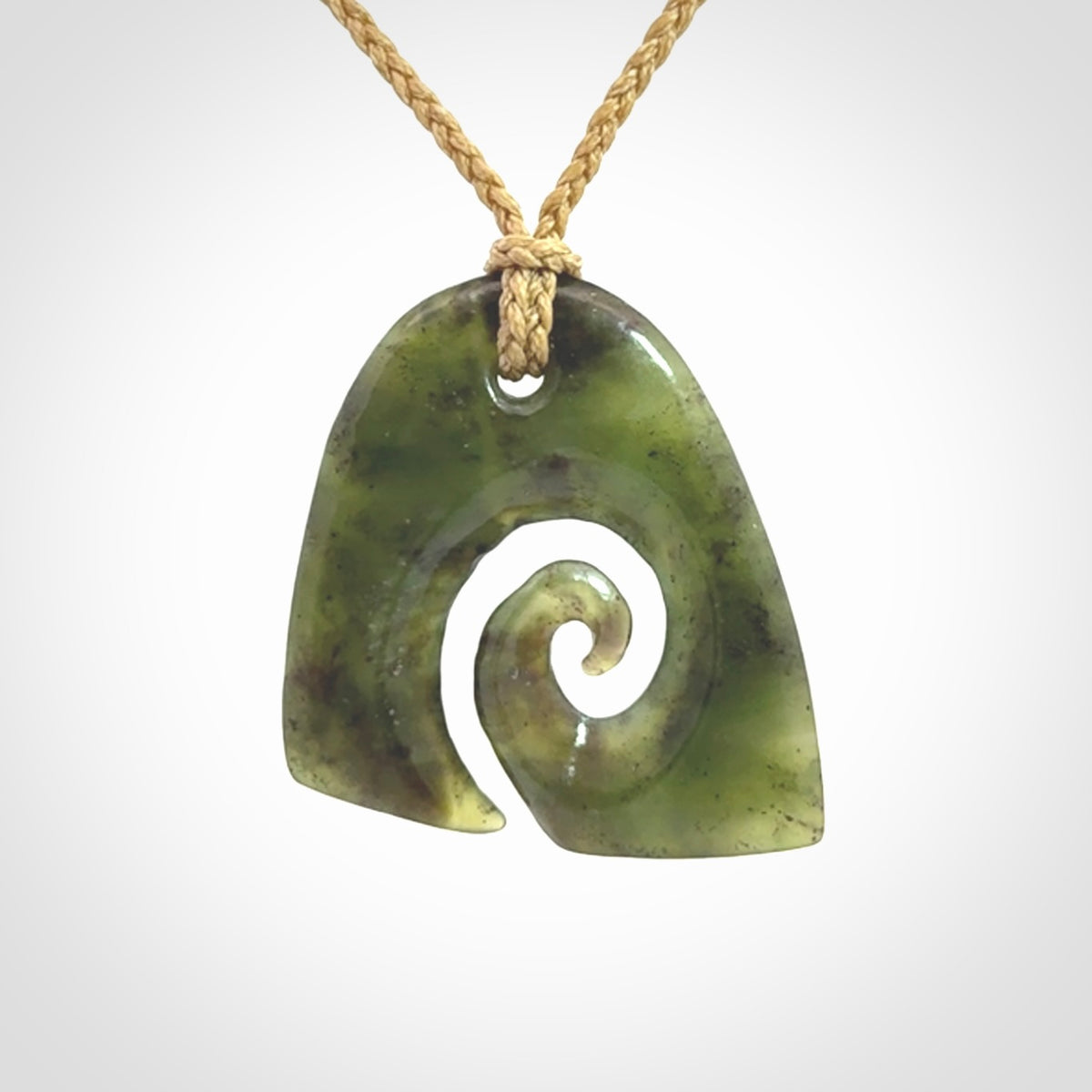 This photo shows a contemporary koru pendant carved from New Zealand Jade. We provide this piece with a tan fixed length cord.