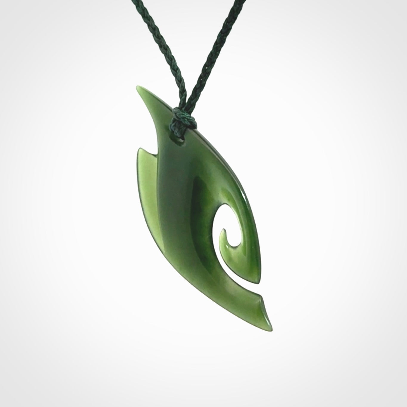 This photo shows a koru pendant carved from New Zealand Jade. We provide this piece with an adjustable green cord.