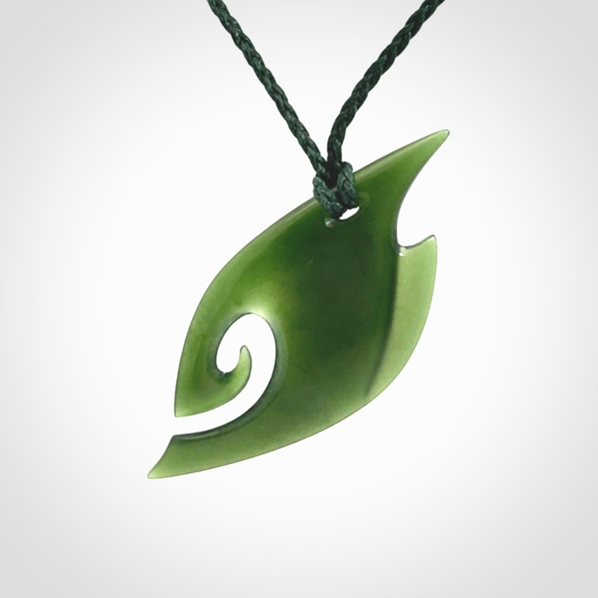 This photo shows a koru pendant carved from New Zealand Jade. We provide this piece with an adjustable green cord.