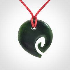 This photo shows a koru pendant carved from New Zealand Jade. We provide this piece with an adjustable red cord.