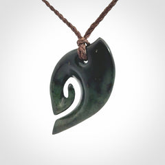 This photo shows a koru pendant carved from New Zealand Jade. We provide this piece with an adjustable brown cord.