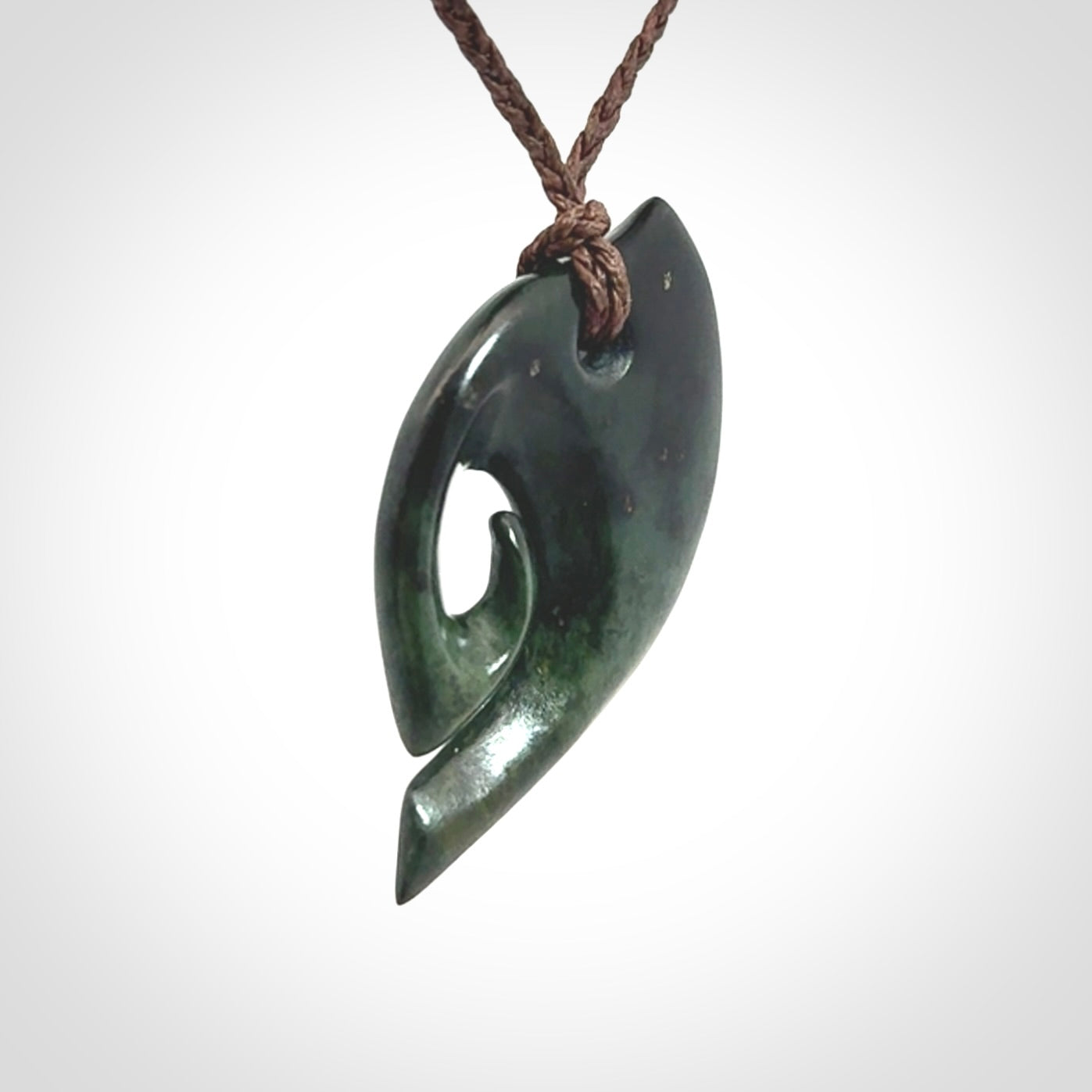 This photo shows a koru pendant carved from New Zealand Jade. We provide this piece with an adjustable brown cord.