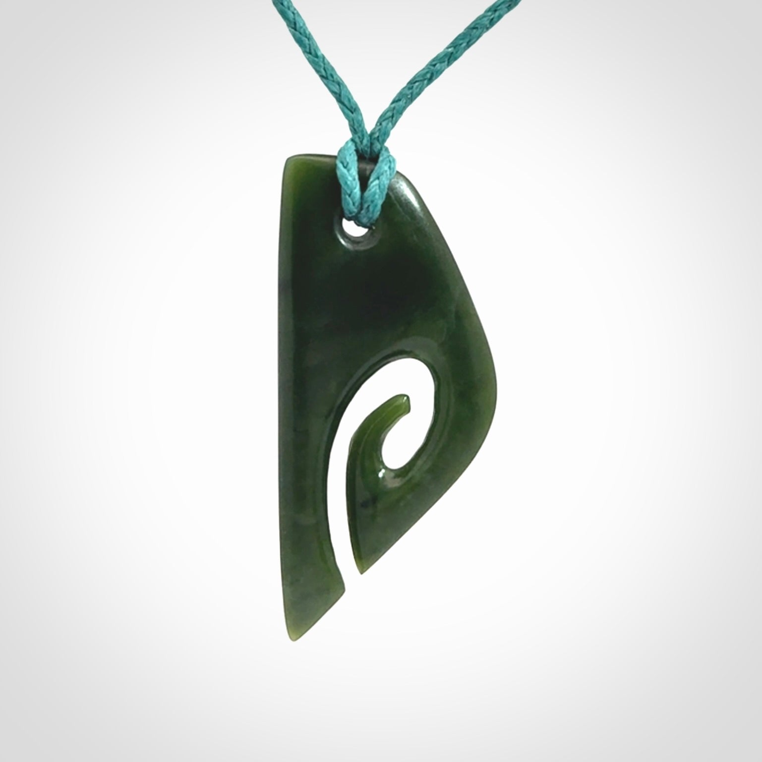 This photo shows a koru pendant carved from New Zealand Jade. We provide this piece with an adjustable blue cord.