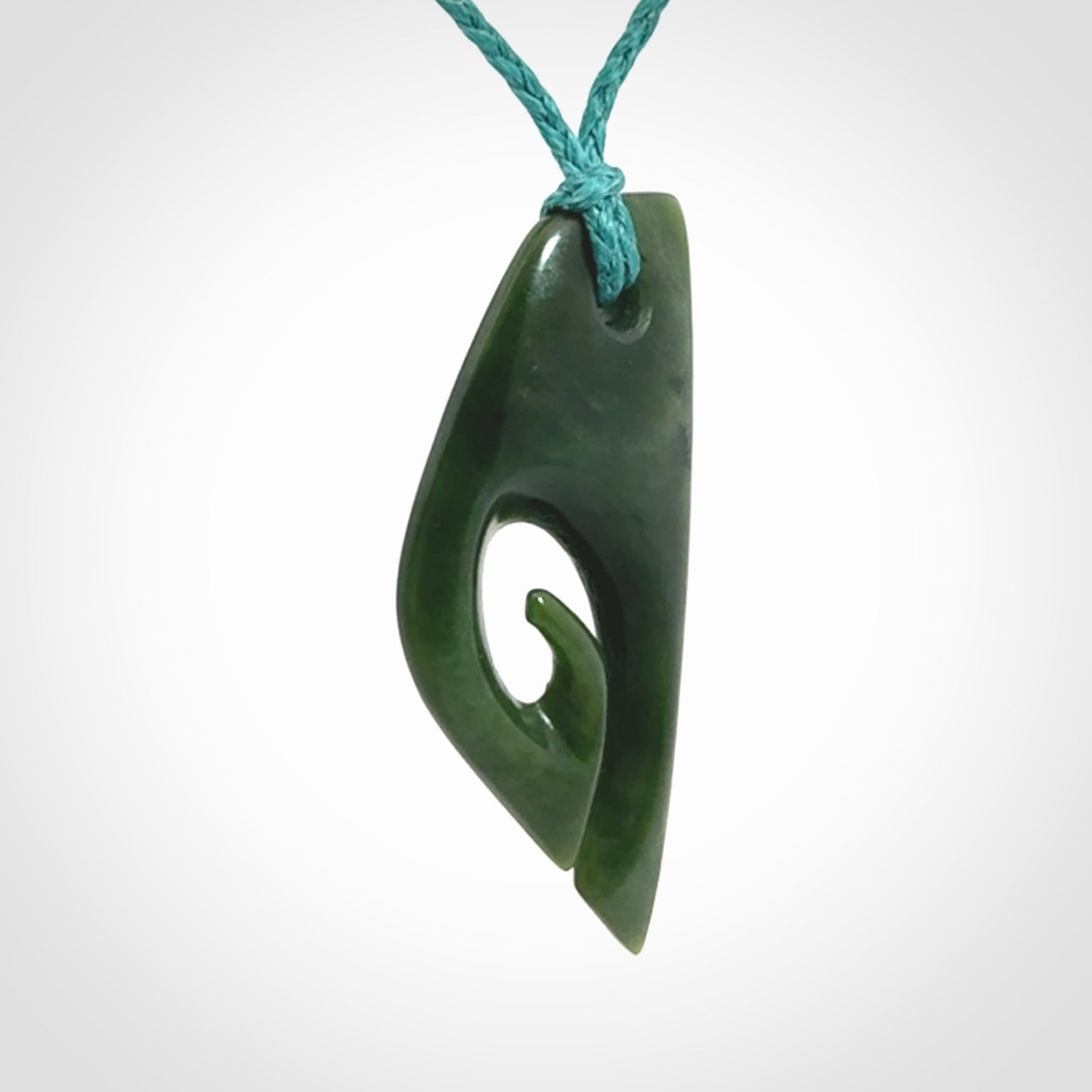 This photo shows a koru pendant carved from New Zealand Jade. We provide this piece with an adjustable blue cord.