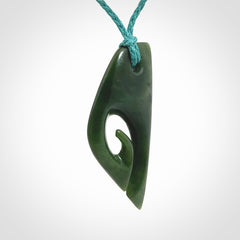 This photo shows a koru pendant carved from New Zealand Jade. We provide this piece with an adjustable blue cord.