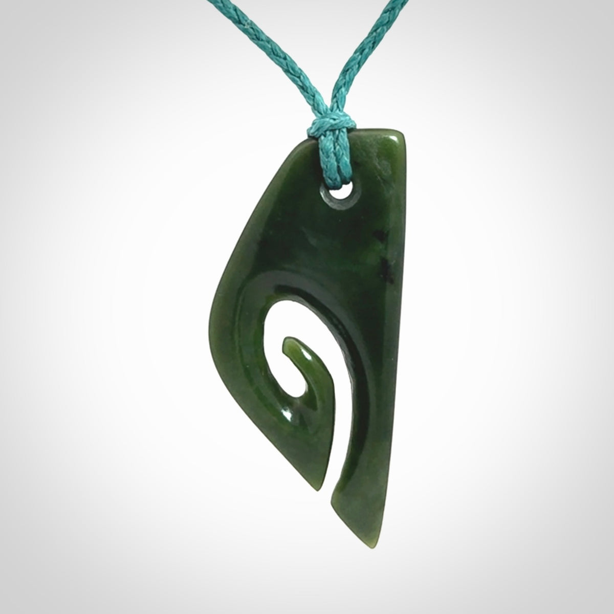 This photo shows a koru pendant carved from New Zealand Jade. We provide this piece with an adjustable blue cord.