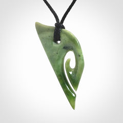 This photo shows a koru pendant carved from New Zealand Jade. We provide this piece with an adjustable black cord.