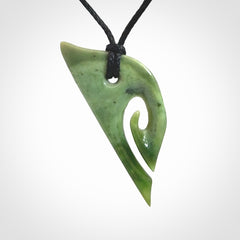 This photo shows a koru pendant carved from New Zealand Jade. We provide this piece with an adjustable black cord.