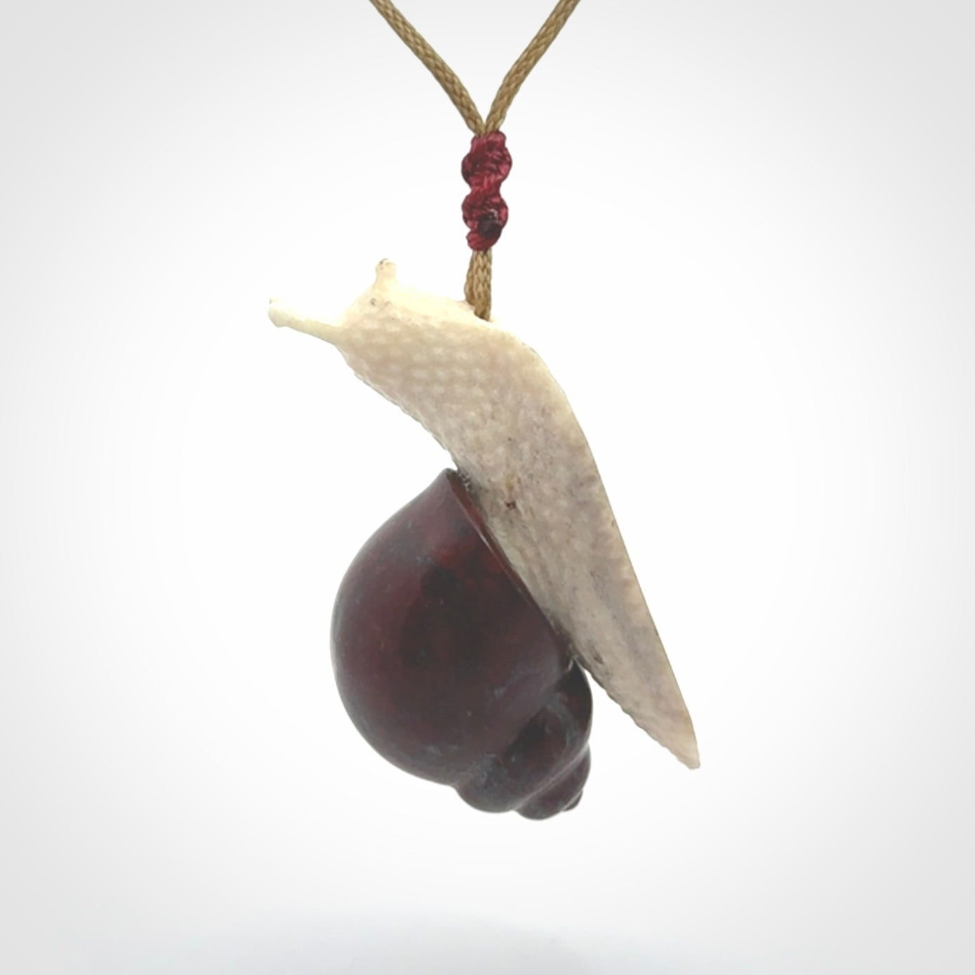 Snail design pendant carved in red jasper with bone. Real jasper and bone jewellery for sale online with NZ Pacific.