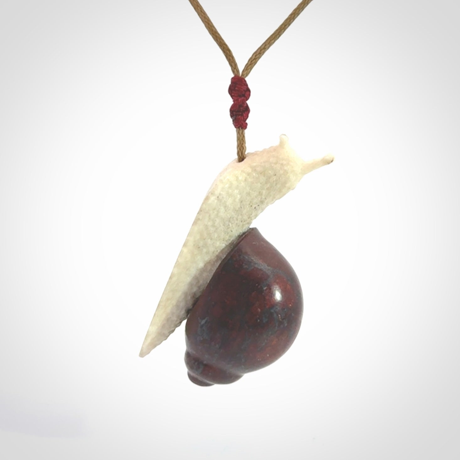Snail design pendant carved in red jasper with bone. Real jasper and bone jewellery for sale online with NZ Pacific.
