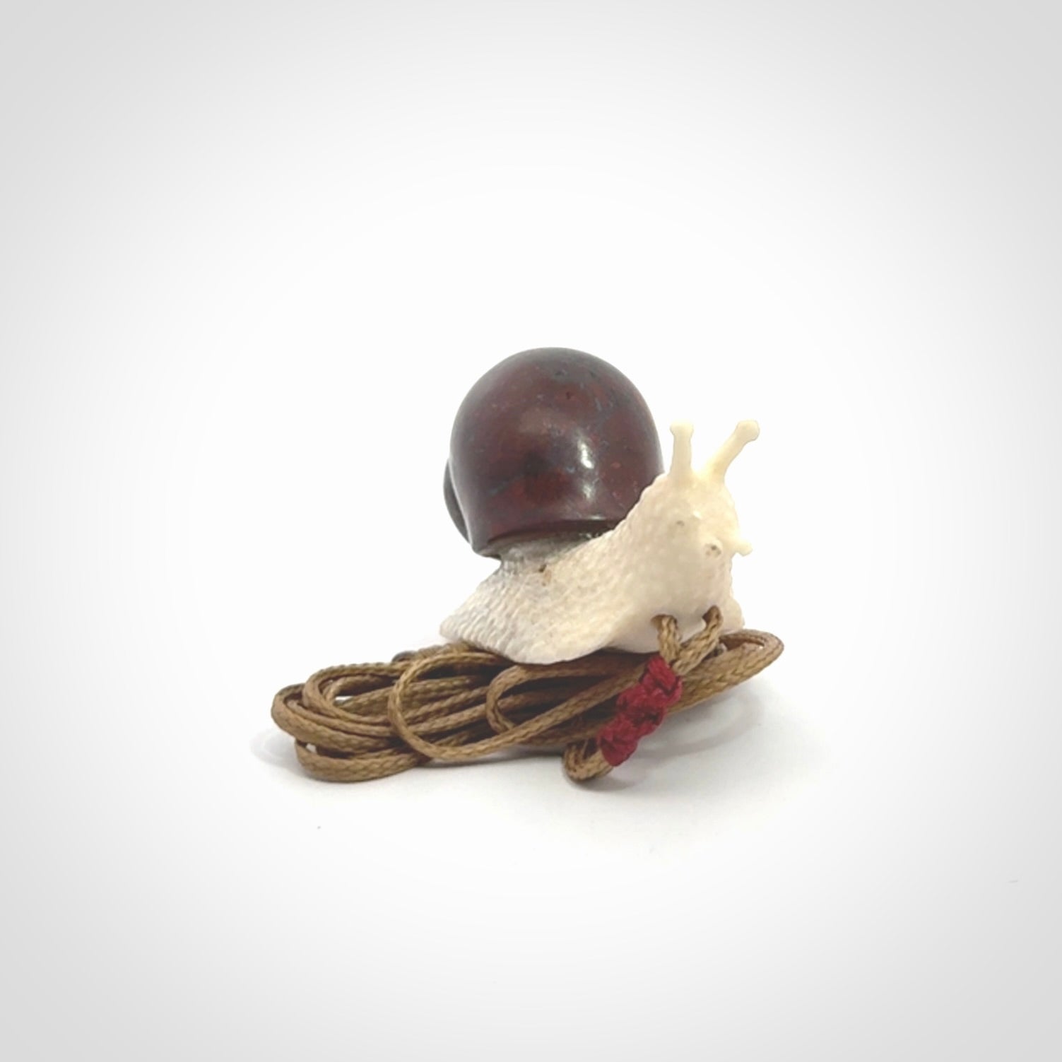 Snail design pendant carved in red jasper with bone. Real jasper and bone jewellery for sale online with NZ Pacific.