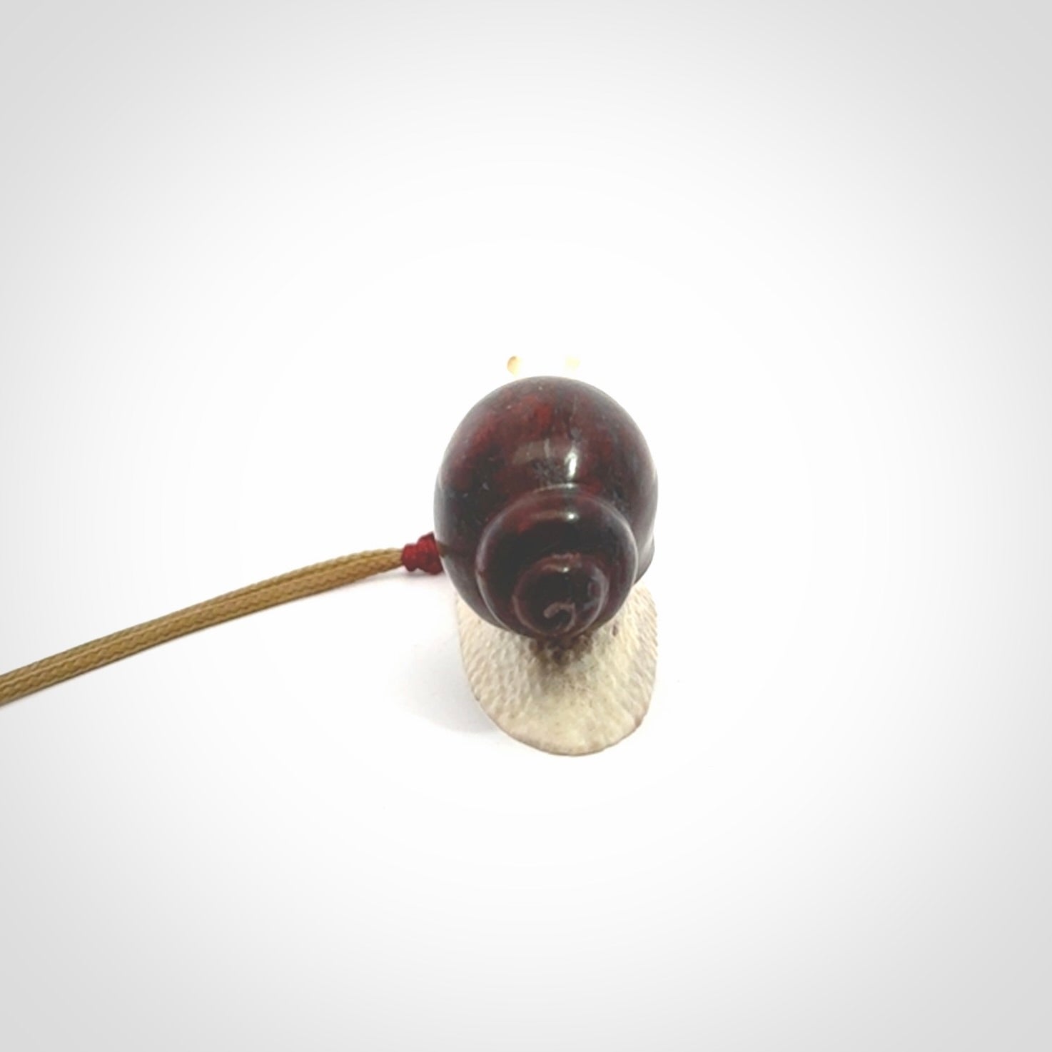 Snail design pendant carved in red jasper with bone. Real jasper and bone jewellery for sale online with NZ Pacific.
