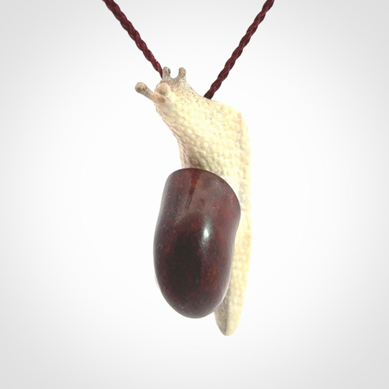 Snail design pendant carved in red jasper with deer antler. Real jasper and bone jewellery for sale online with NZ Pacific.