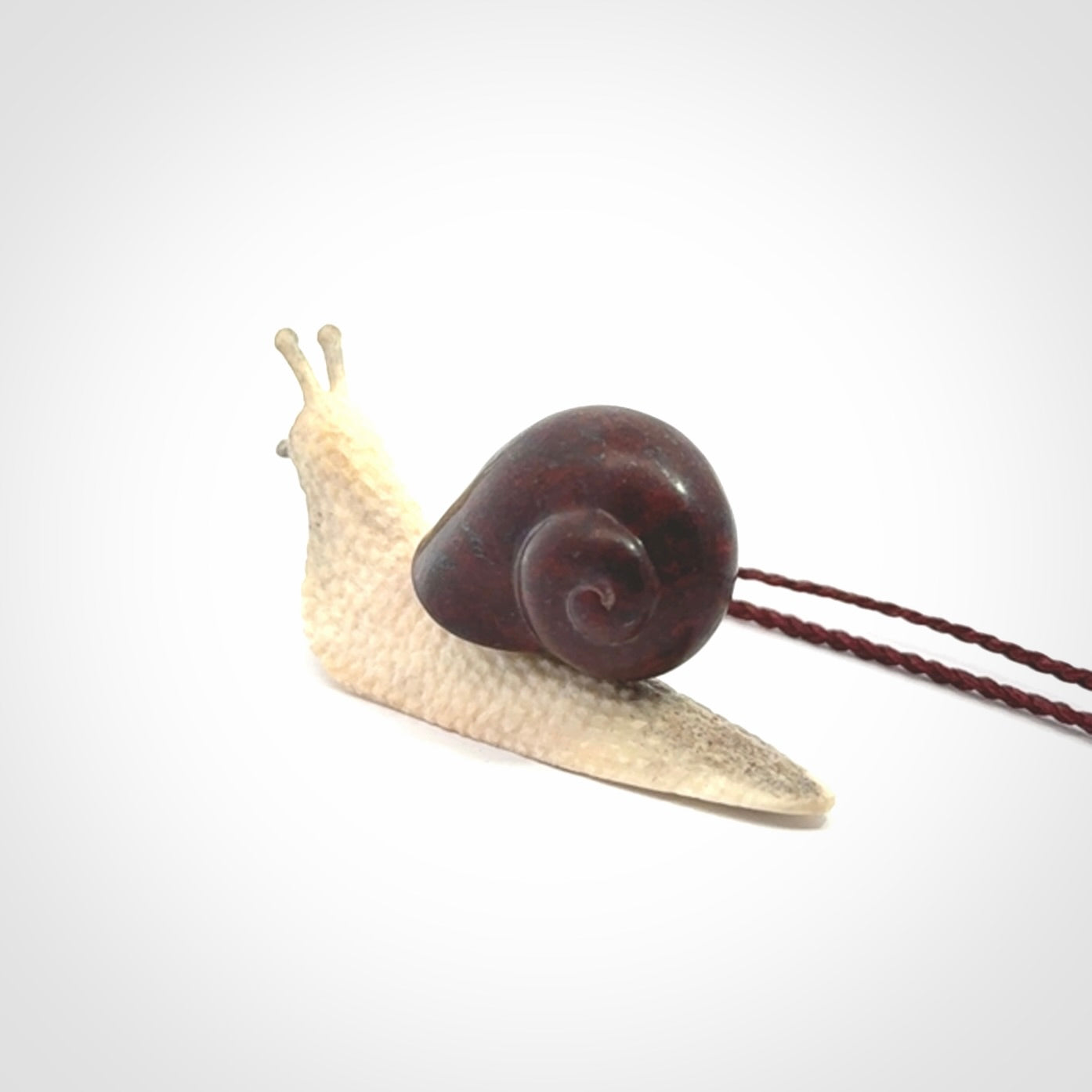 Snail design pendant carved in red jasper with deer antler. Real jasper and bone jewellery for sale online with NZ Pacific.