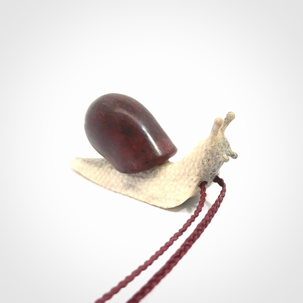 Snail design pendant carved in red jasper with deer antler. Real jasper and bone jewellery for sale online with NZ Pacific.
