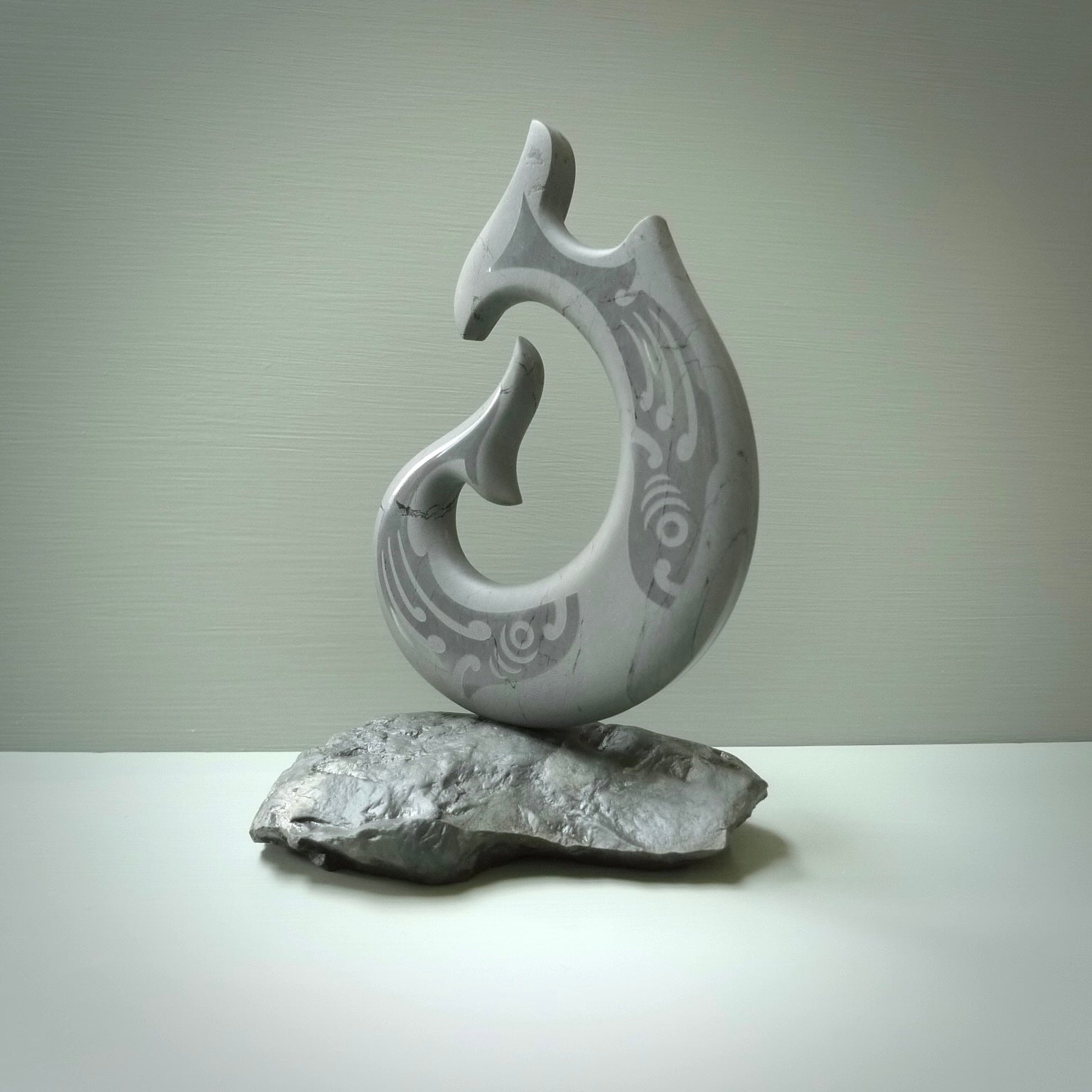 Hand carved large New Zealand Argillite Stone Matau, hook carving displayed in a New Zealand Pākohe stand sculpture. Hand carved here in New Zealand by Kerry Thompson. This is a 'one only' sculpture, a beautiful display piece.
