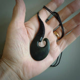 This picture shows a large deep green large jade hook pendant, also called a hei-matau, carved for us in New Zealand jade. The carver is Donna Summers - and this is a beautiful example of his work. The cord is a four-plait, adjustable black coloured necklace. 