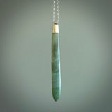 This picture shows a hand carved Inanga Pounamu, jade drop pendant with sterling silver cap and chain. The jade is a very dark green with a shimmer of light blue tones in the stone. It is suspended from a sterling silver clasp and we supply a sterling silver chain. Delivery is free worldwide.