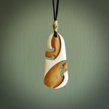 A hand carved bone toki with double koru, intricate pendant. The cord is a black colour and is adjustable. A medium sized hand made toki with koru necklace by New Zealand artist Tonijae Brockway. Tonijae has stained parts of the bone which really add to the dimension of this pendant. One off work of art to wear.