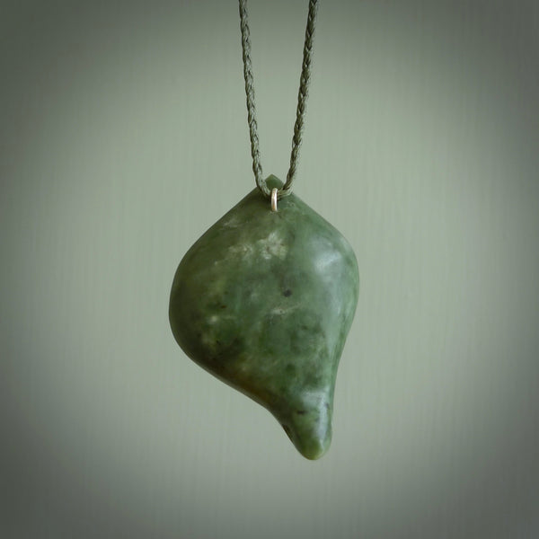 This picture shows a hand carved drop pendant made from a deep green coloured New Zealand Pounamu, jade. The front face is a concave, cupped design and the back is round. It is provided with an adjustable fern green cord in a woven kete pouch. Shipped to you with Express Courier.